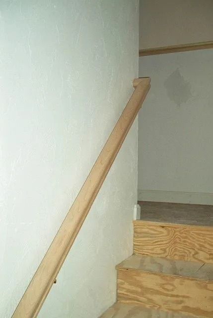Wooden handrail beside carpeted stairs in a hallway