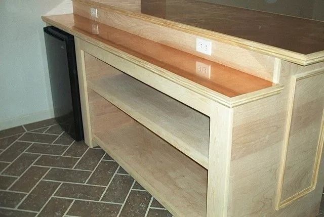 Wooden reception counter with a raised top shelf and tiled floor beside it