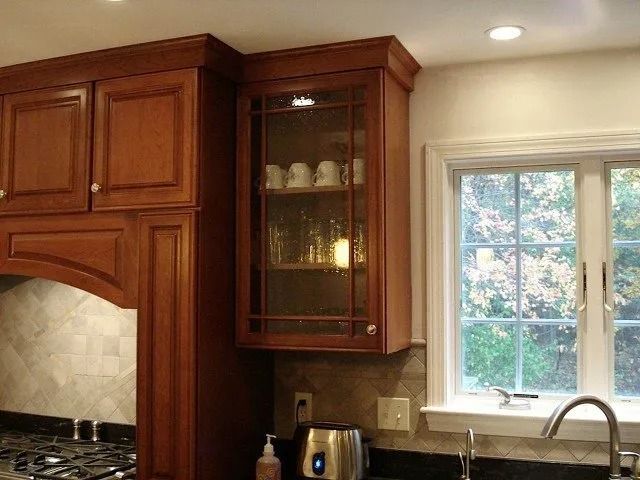 Wooden kitchen cabinets beside a window over a countertop and sink