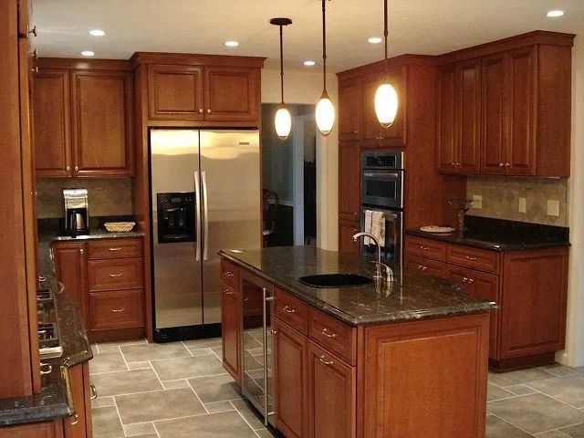 Modern kitchen with cherry cabinets, stainless steel fridge, granite island, and pendant lights
