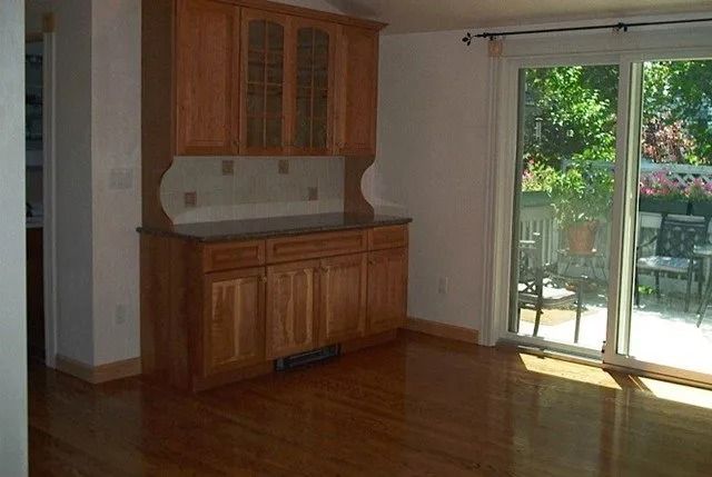 Empty kitchen nook with wooden cabinets and sliding glass door to a patio