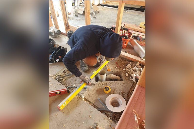 Man On A Hoodie Measuring The Spaces Using A Meter Stick – Hamilton, NZ – Jamark Plumbing