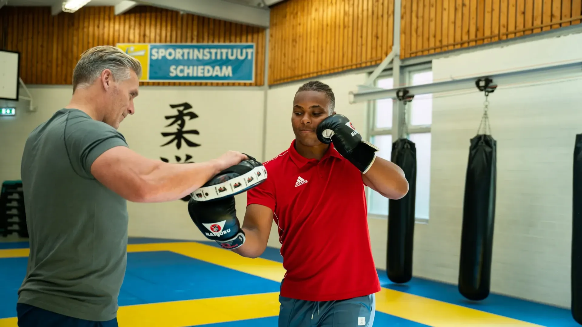 Een man en een vrouw zijn aan het boksen in een sportschool.