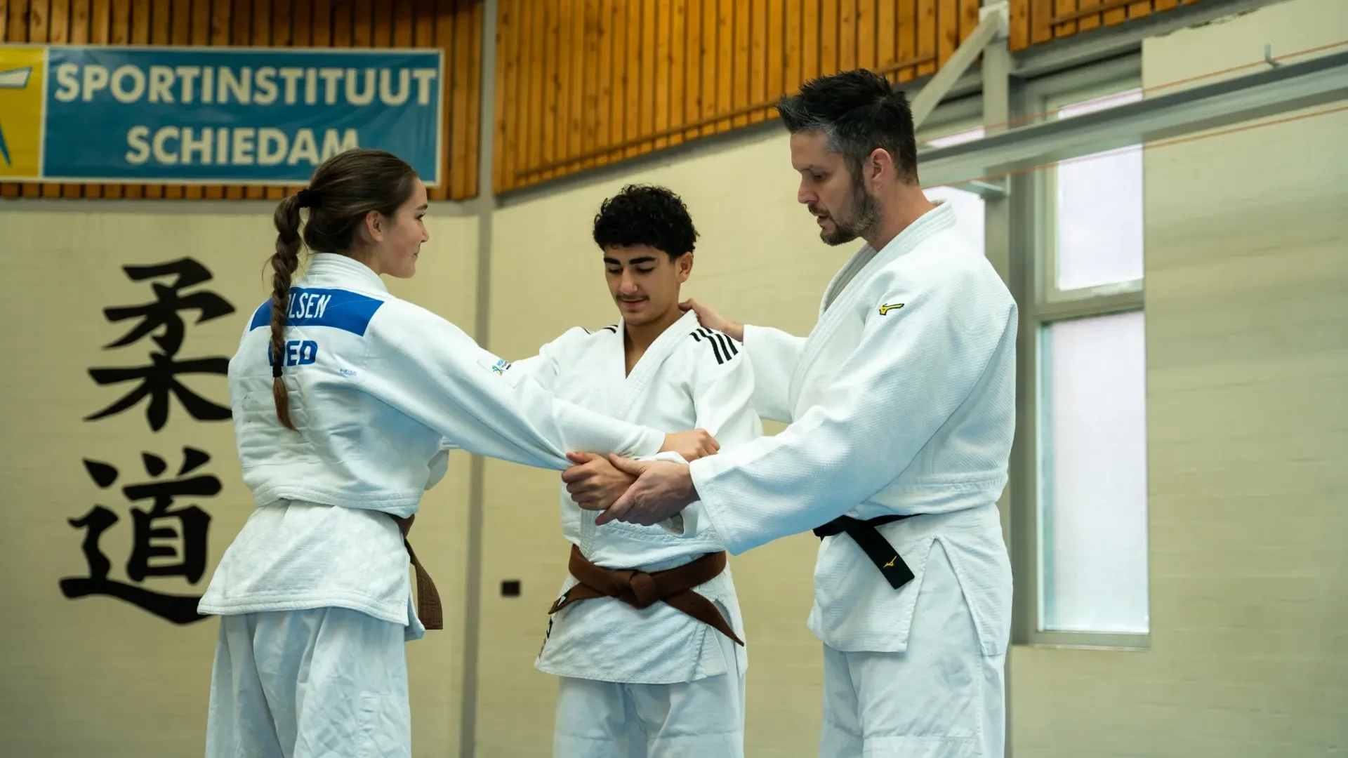 Een groep mensen beoefent judo in een sportschool.
