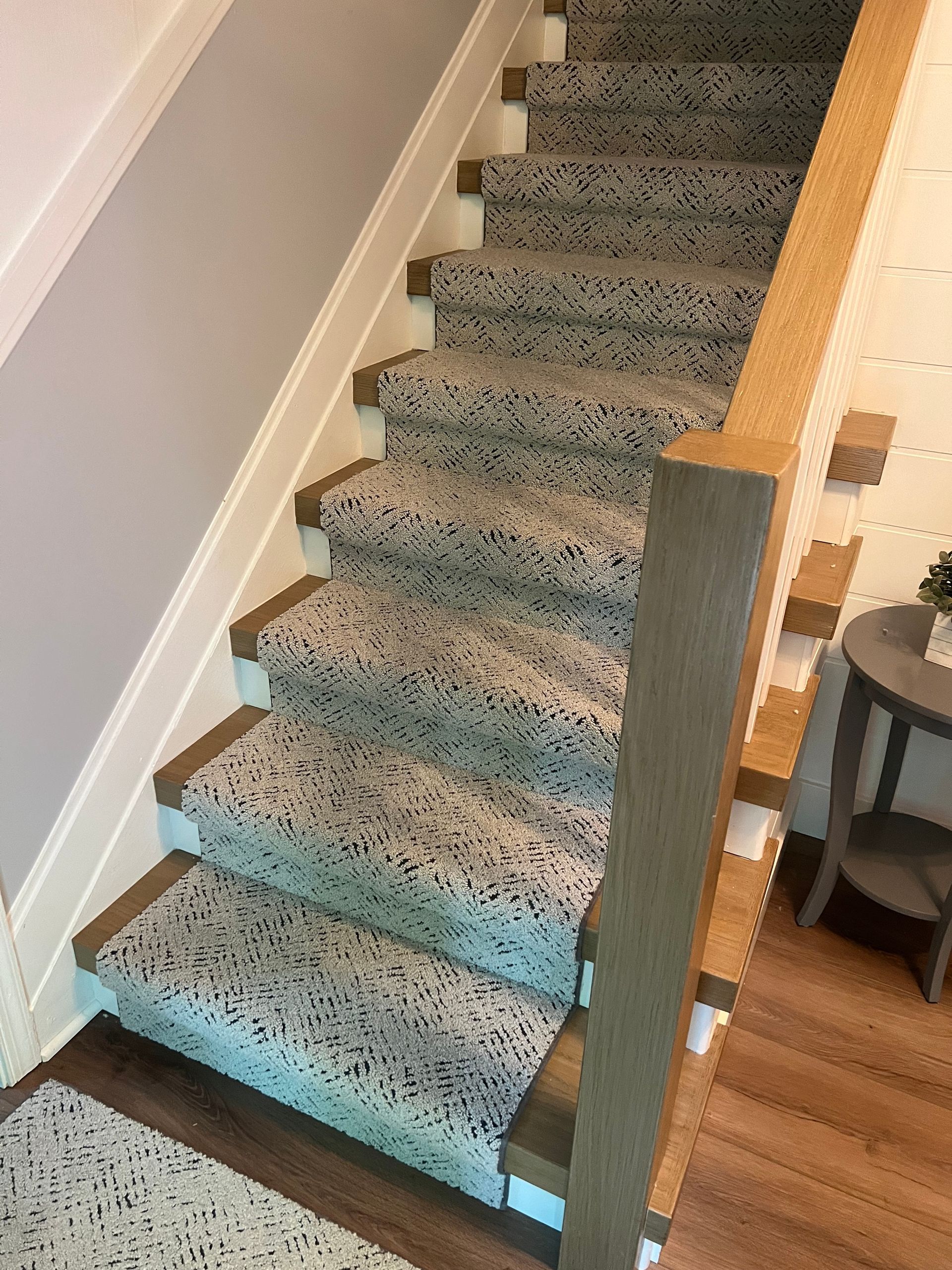 A staircase with a carpet on the steps and a wooden railing.