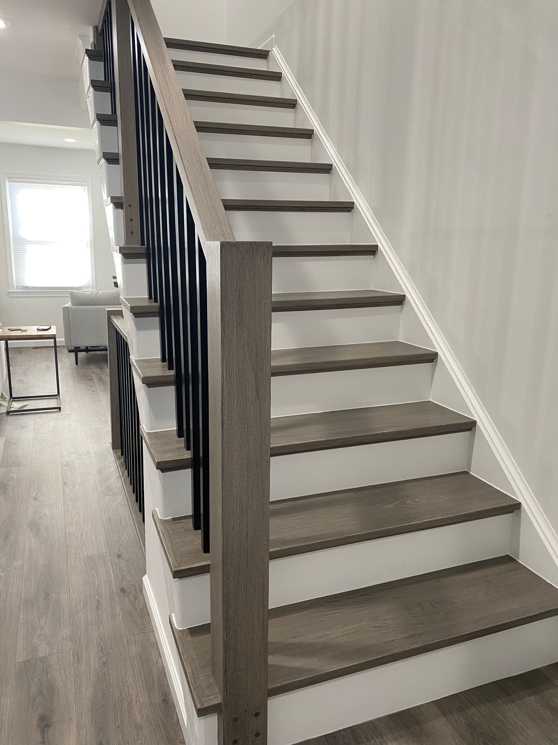 A staircase with wooden steps and a black railing in a living room.