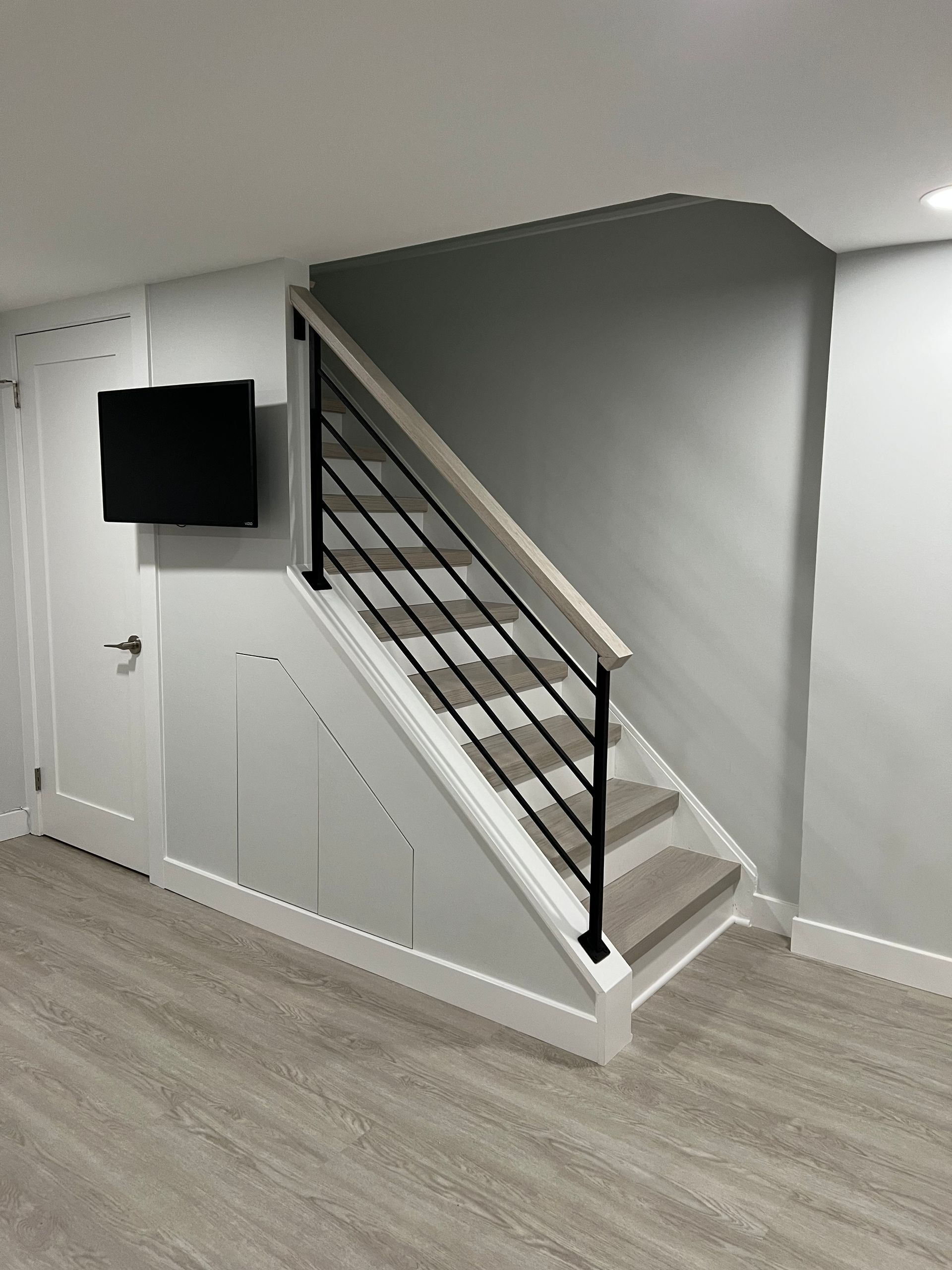 A living room with stairs and a tv on the wall