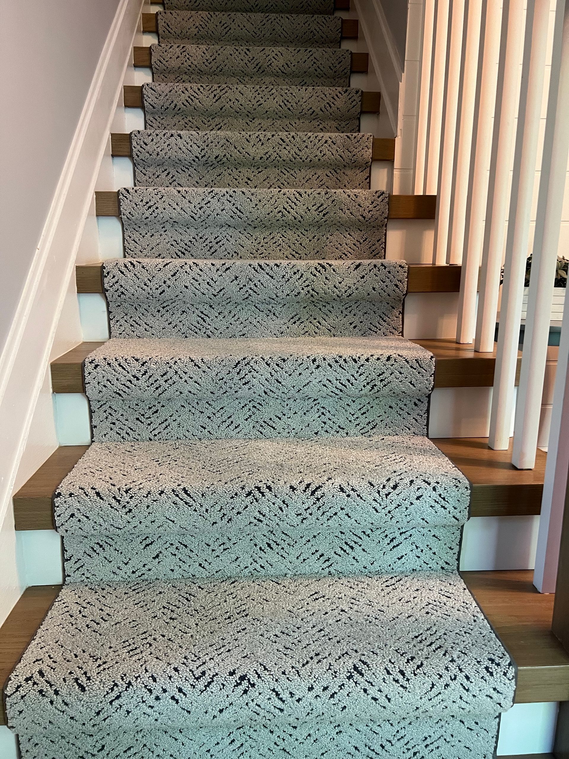 A staircase with a carpet on the steps and a white railing.
