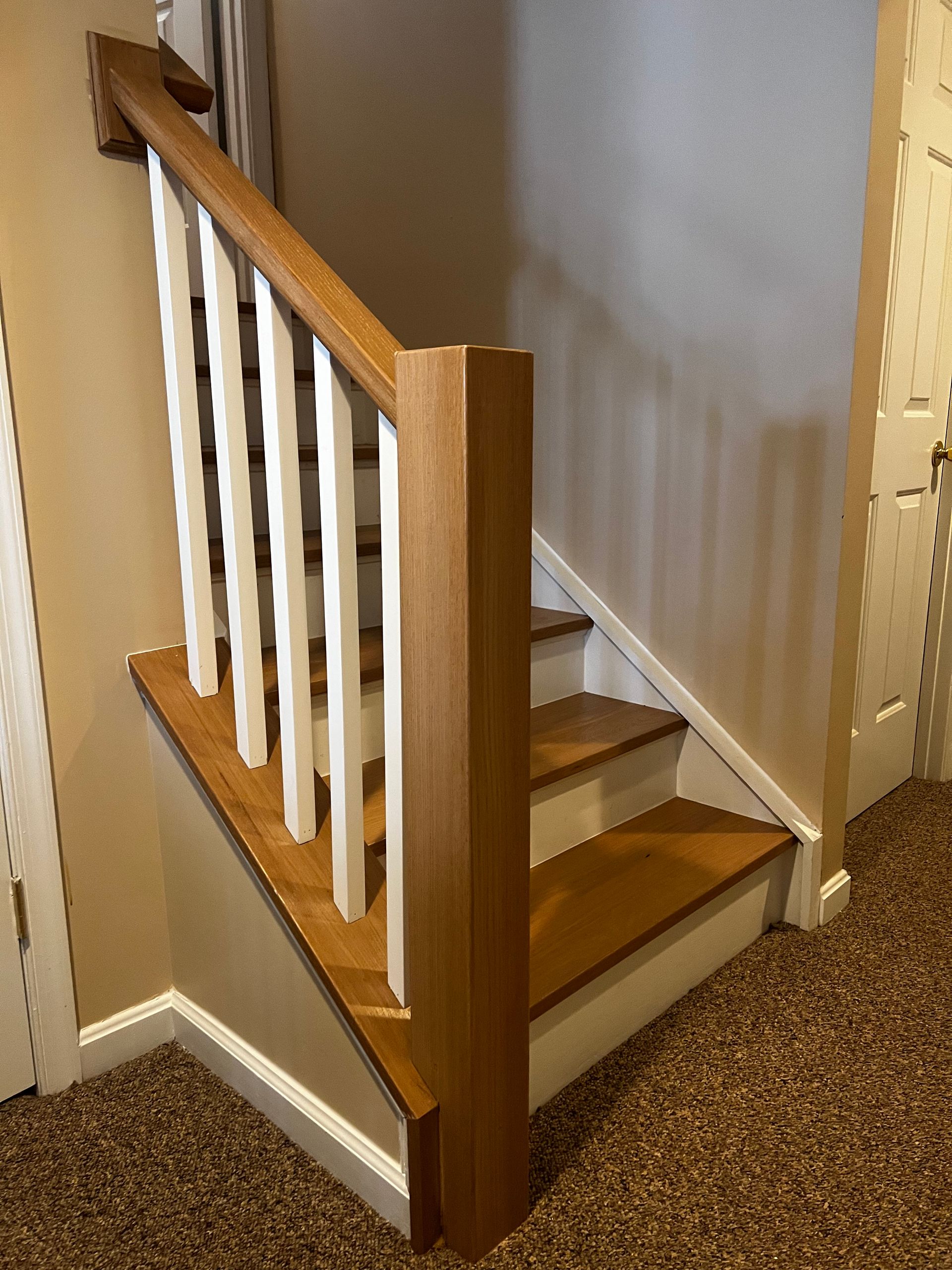 A wooden staircase with a white railing in a house.