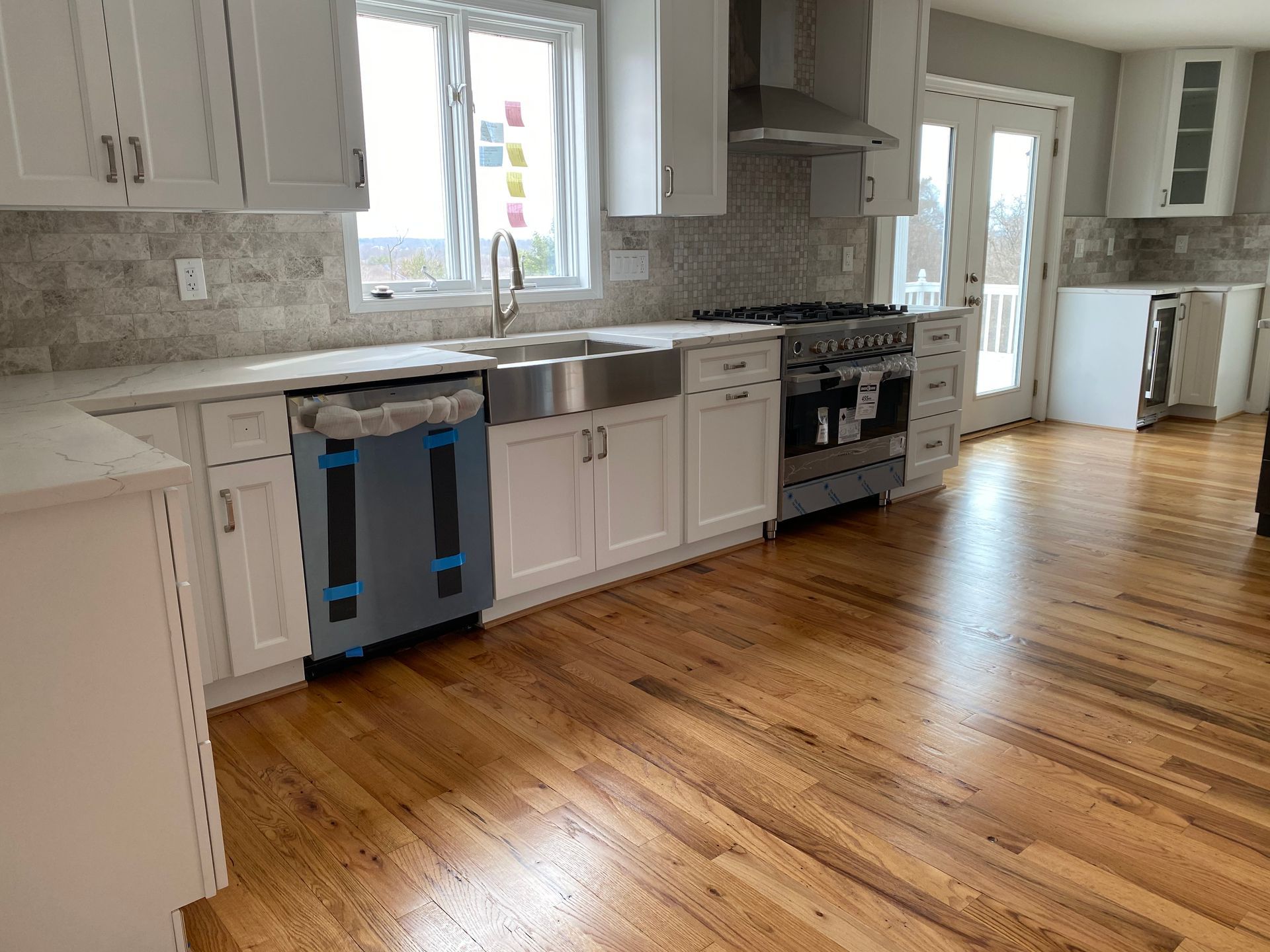 A kitchen with white cabinets , stainless steel appliances , and hardwood floors.