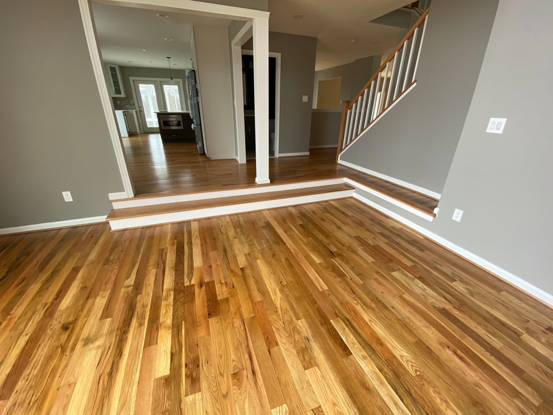 A living room with hardwood floors and stairs in a house.