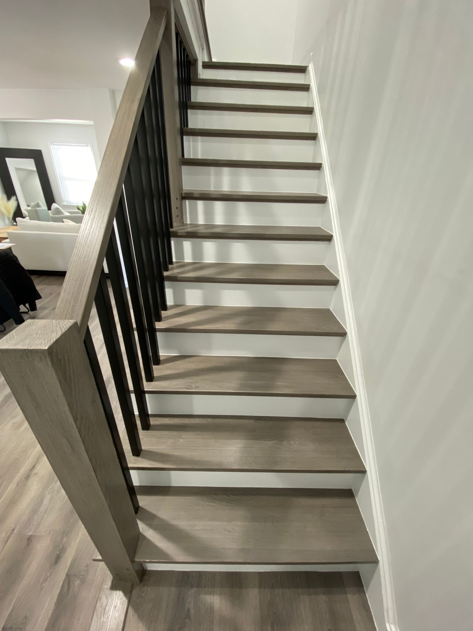 A staircase with wooden steps and a black railing in a living room.
