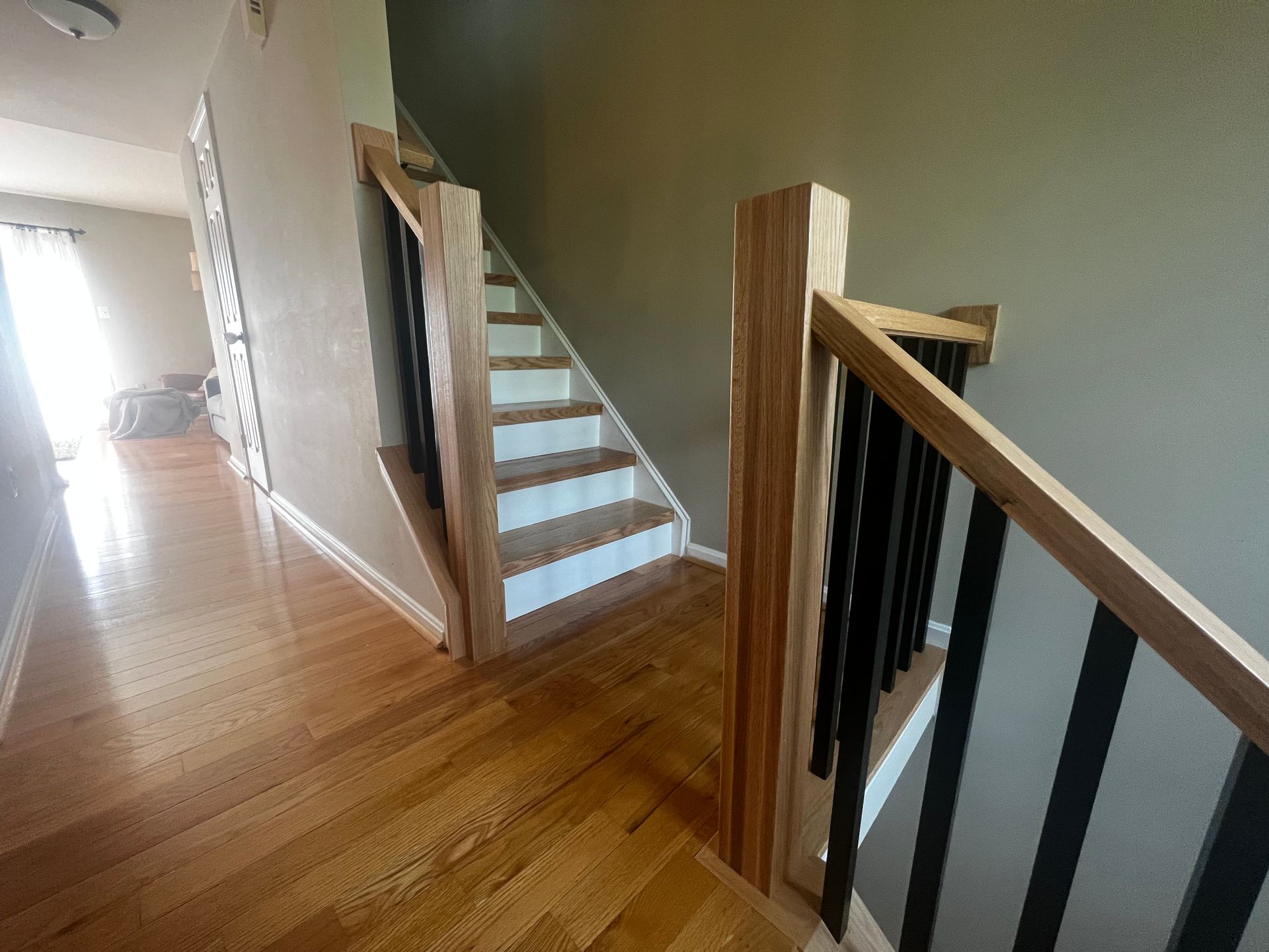 A wooden staircase with white steps and a black railing