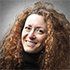 A woman with red curly hair is smiling for the camera.