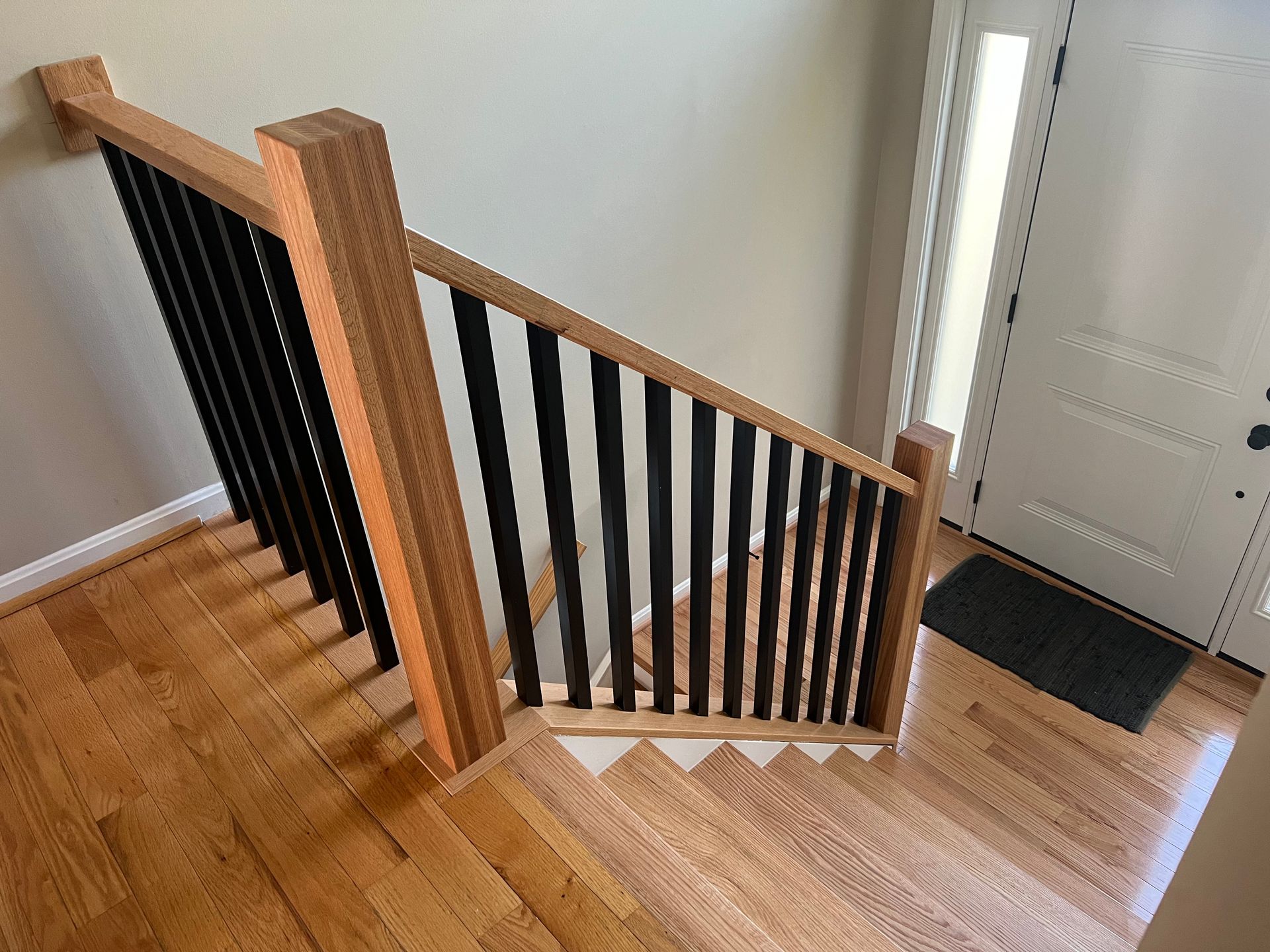 A wooden staircase with a black railing in a house.