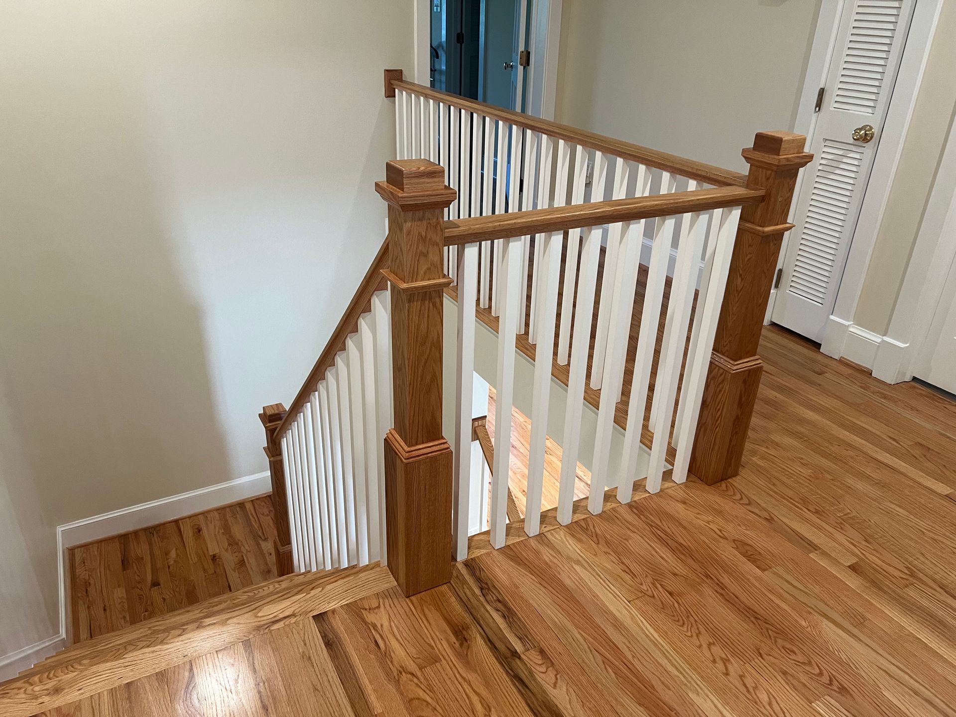 A wooden staircase with white railings and hardwood floors in a house.