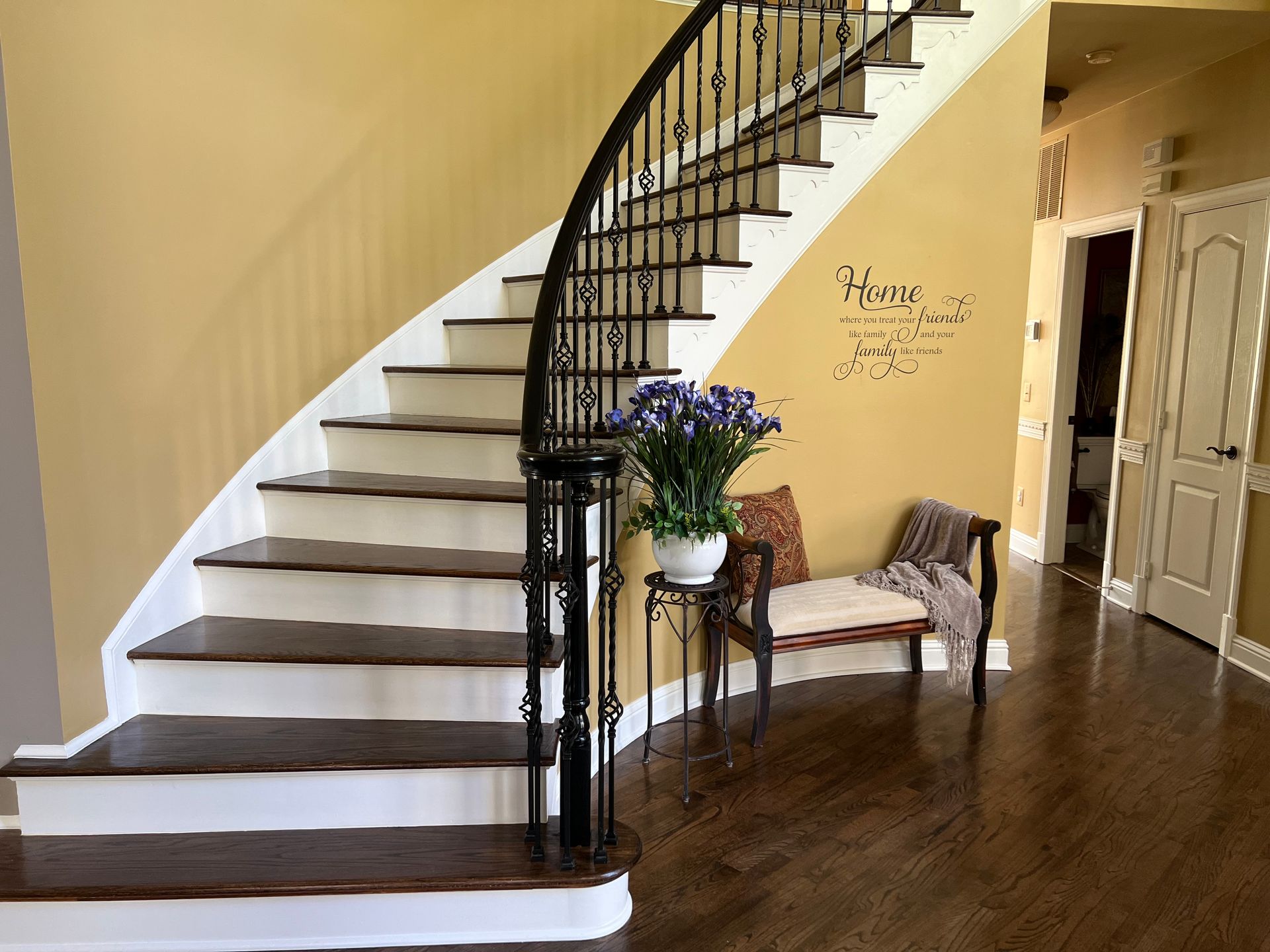 A curved staircase with white steps and a black railing in a house.