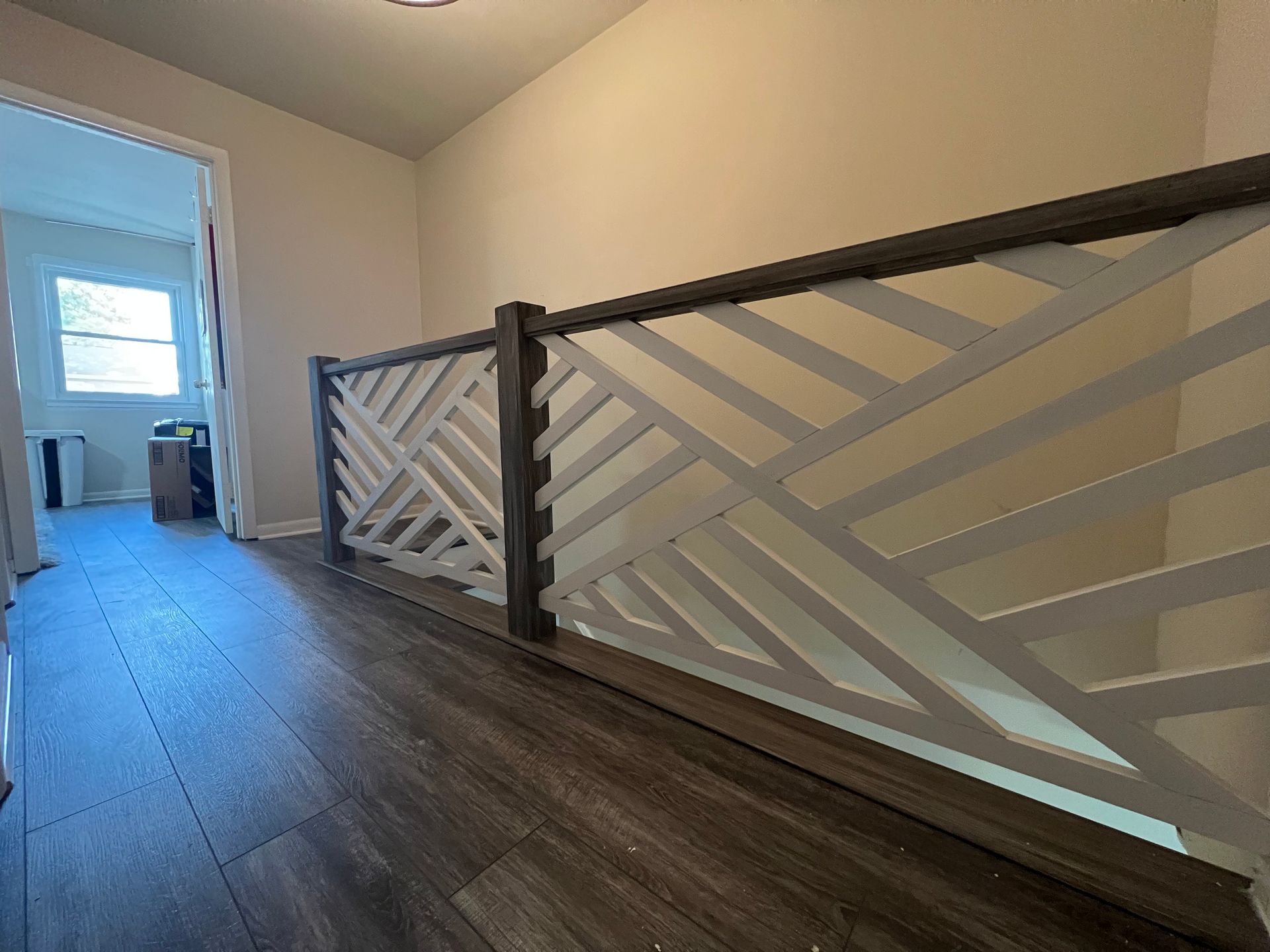 A hallway with a wooden floor and a white railing.
