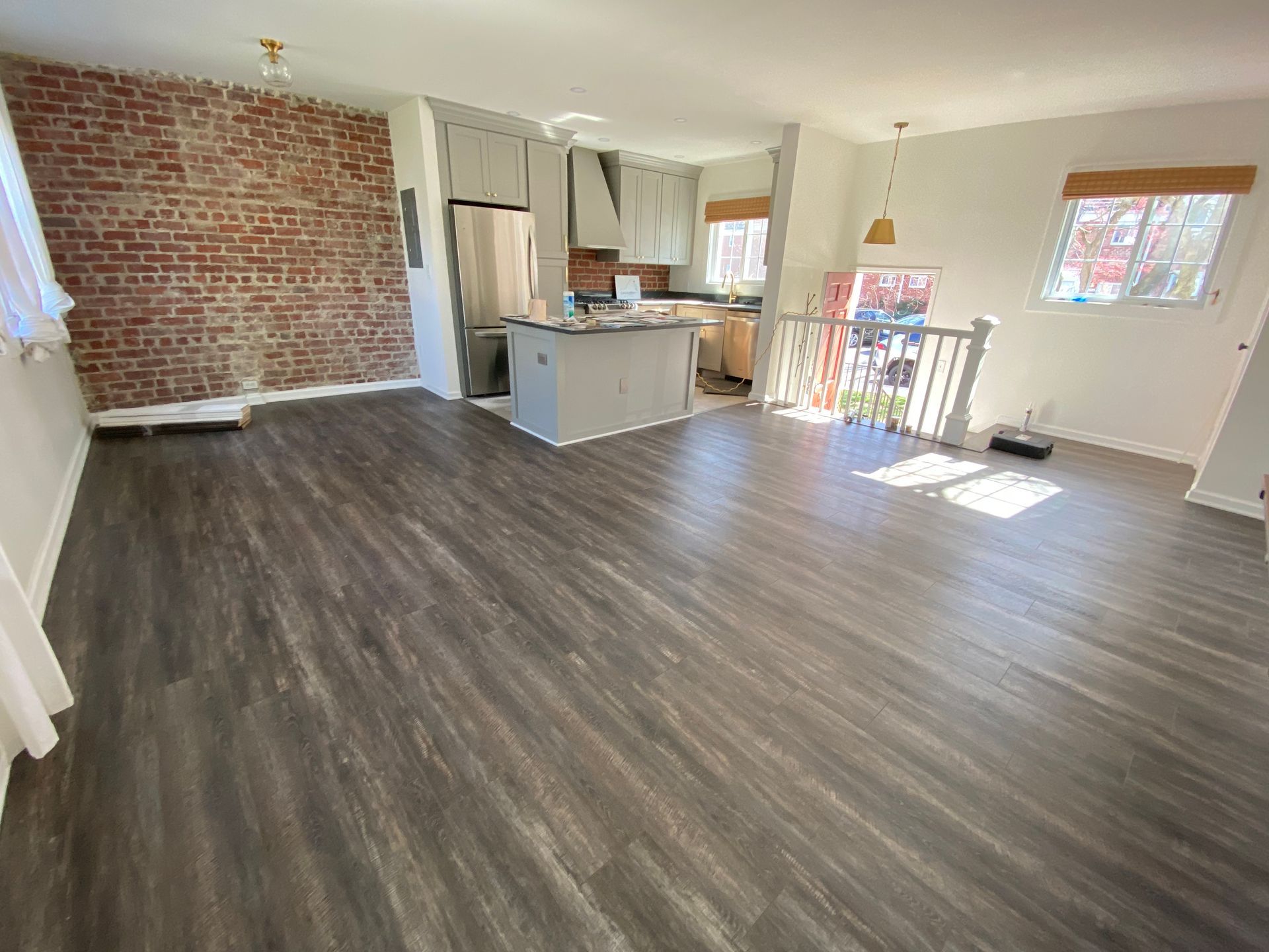 A living room with hardwood floors and a brick wall.
