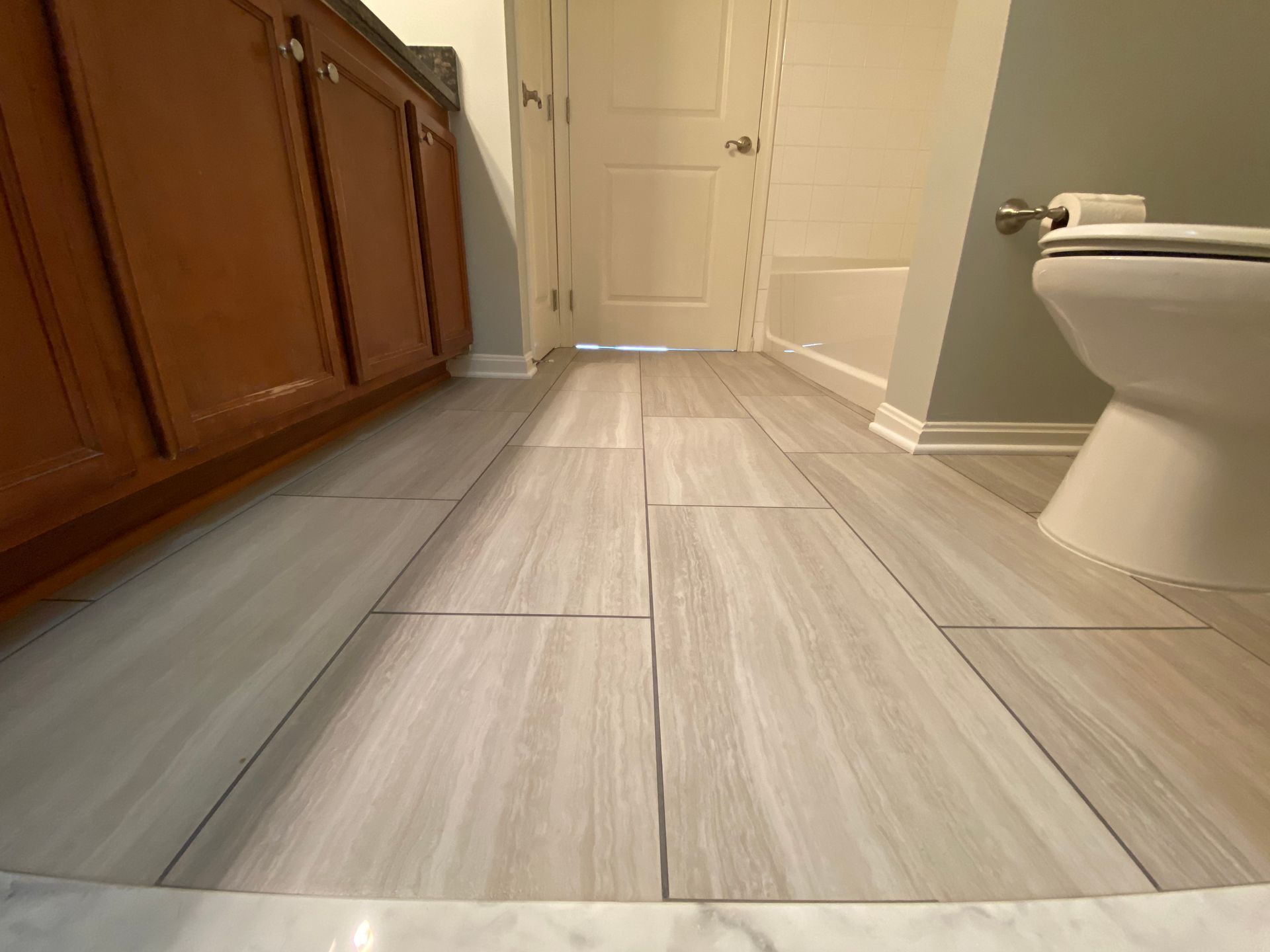 A bathroom with a toilet , sink and wooden cabinets.