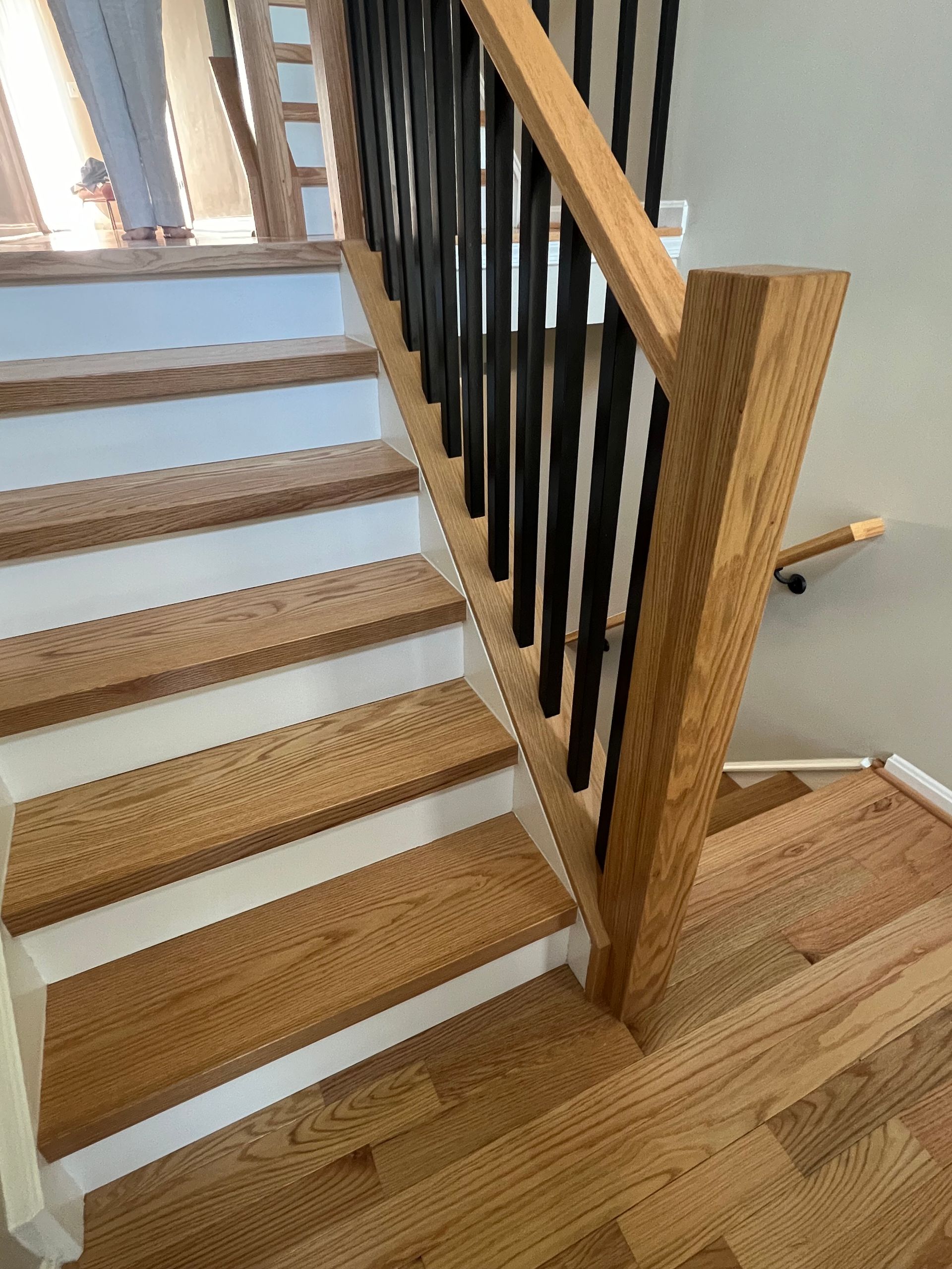 A wooden staircase with white steps and a black railing.