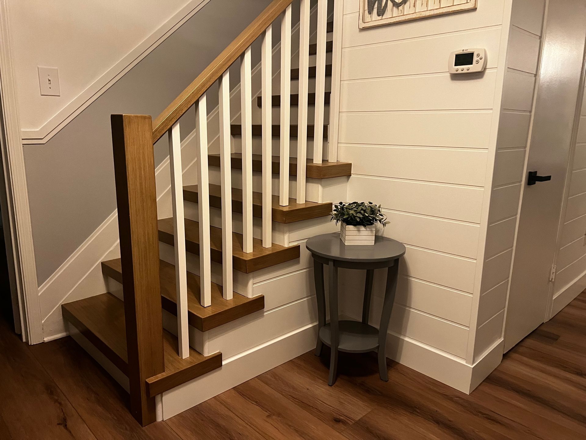 A wooden staircase with white railings is in a hallway next to a table.