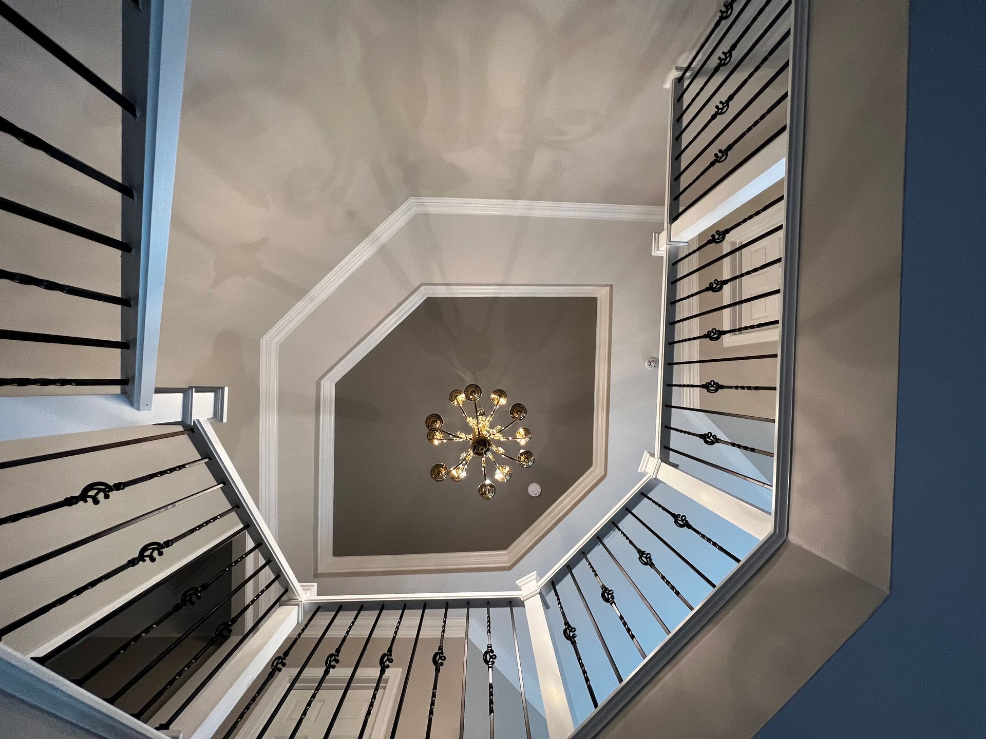 Looking up at a staircase with a chandelier hanging from the ceiling