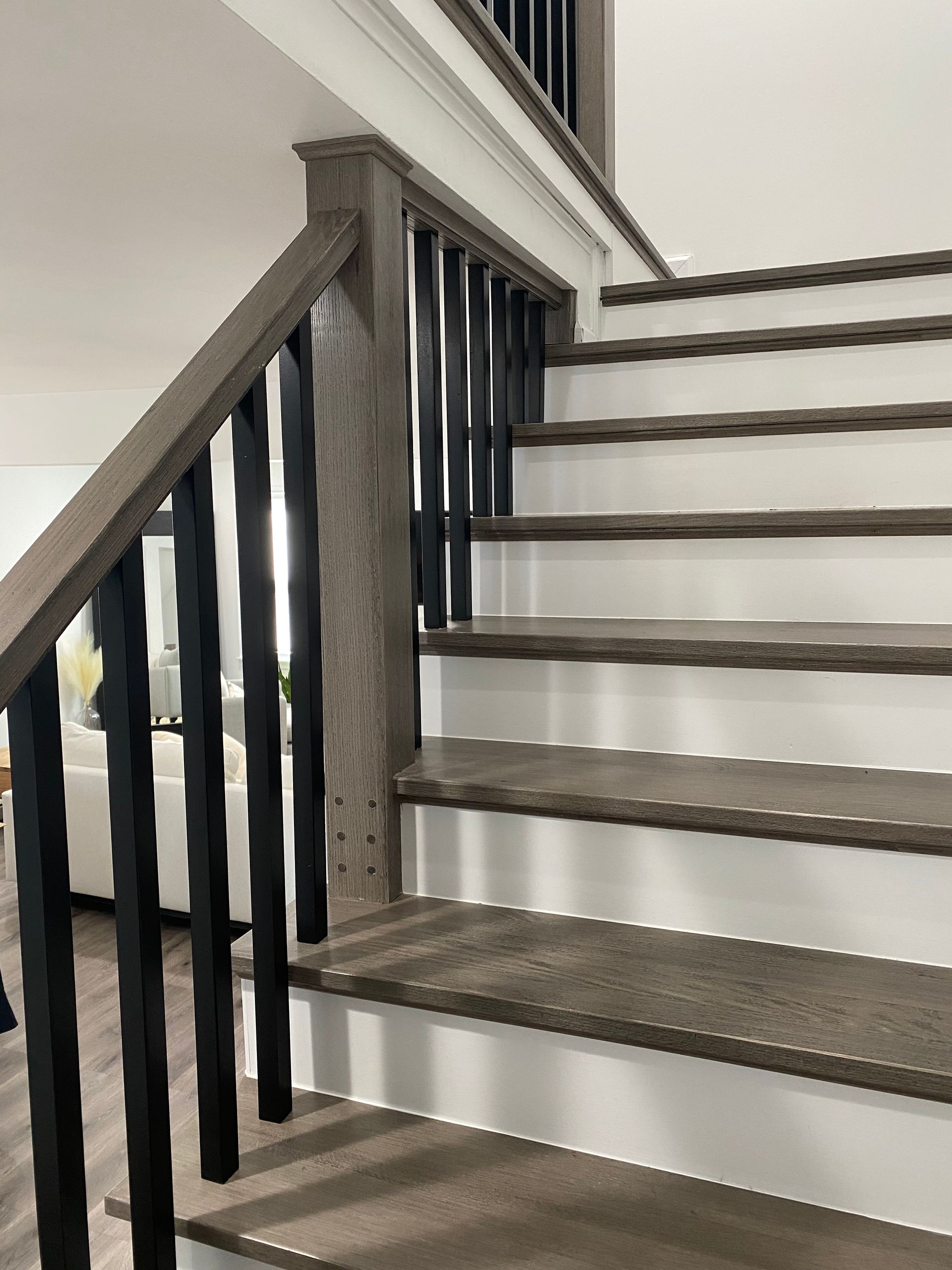 A wooden staircase with a black railing in a living room.