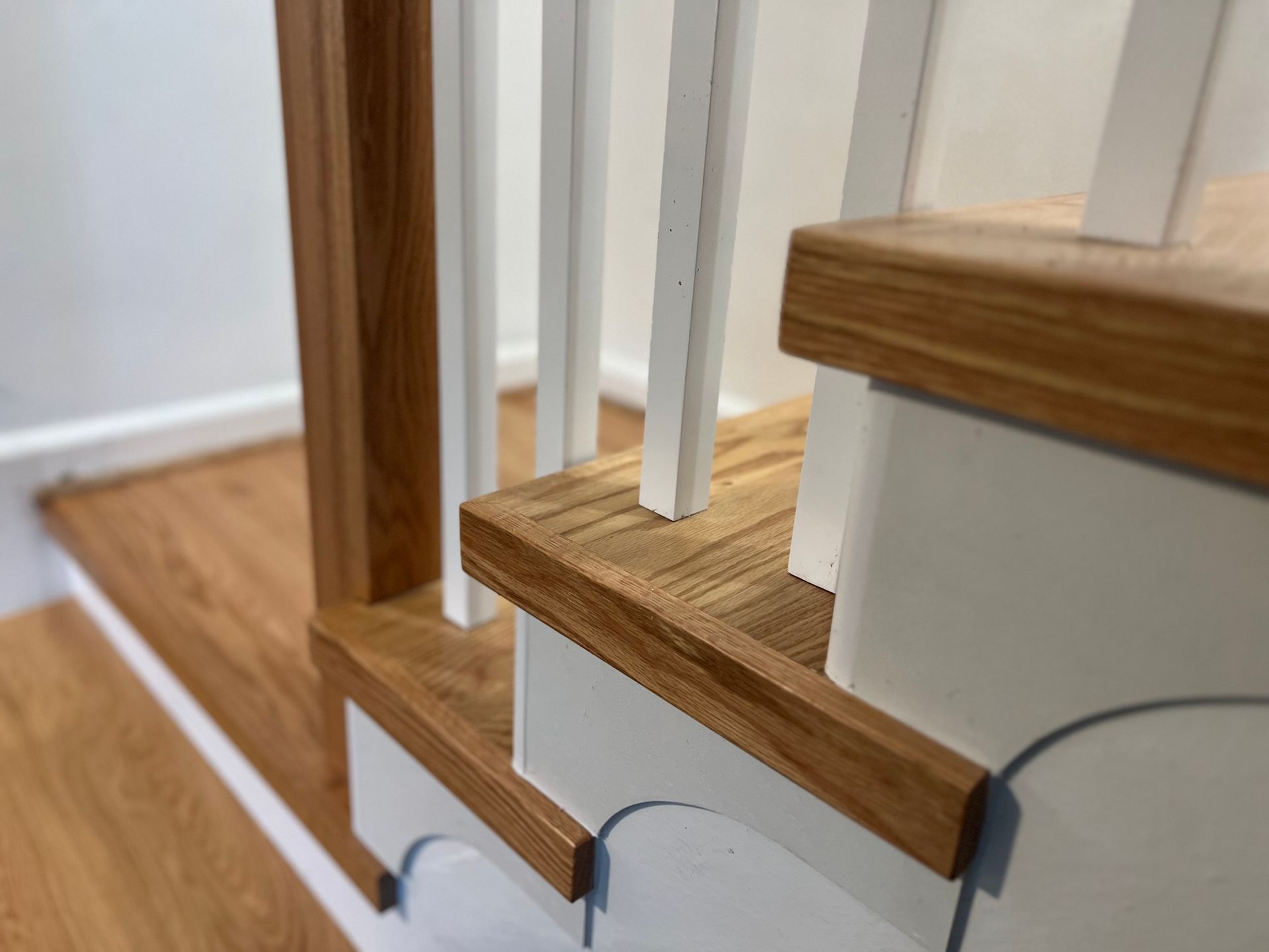 A close up of a wooden staircase with a white railing