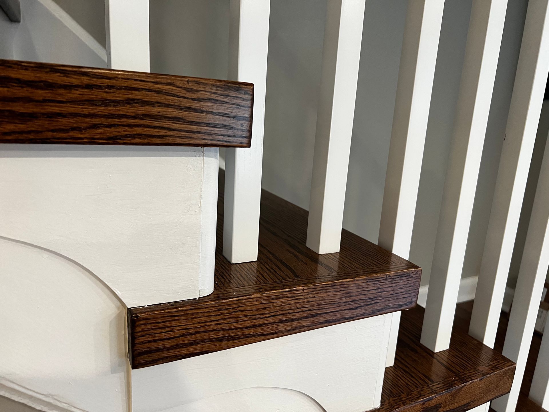 A close up of a wooden staircase with white railing