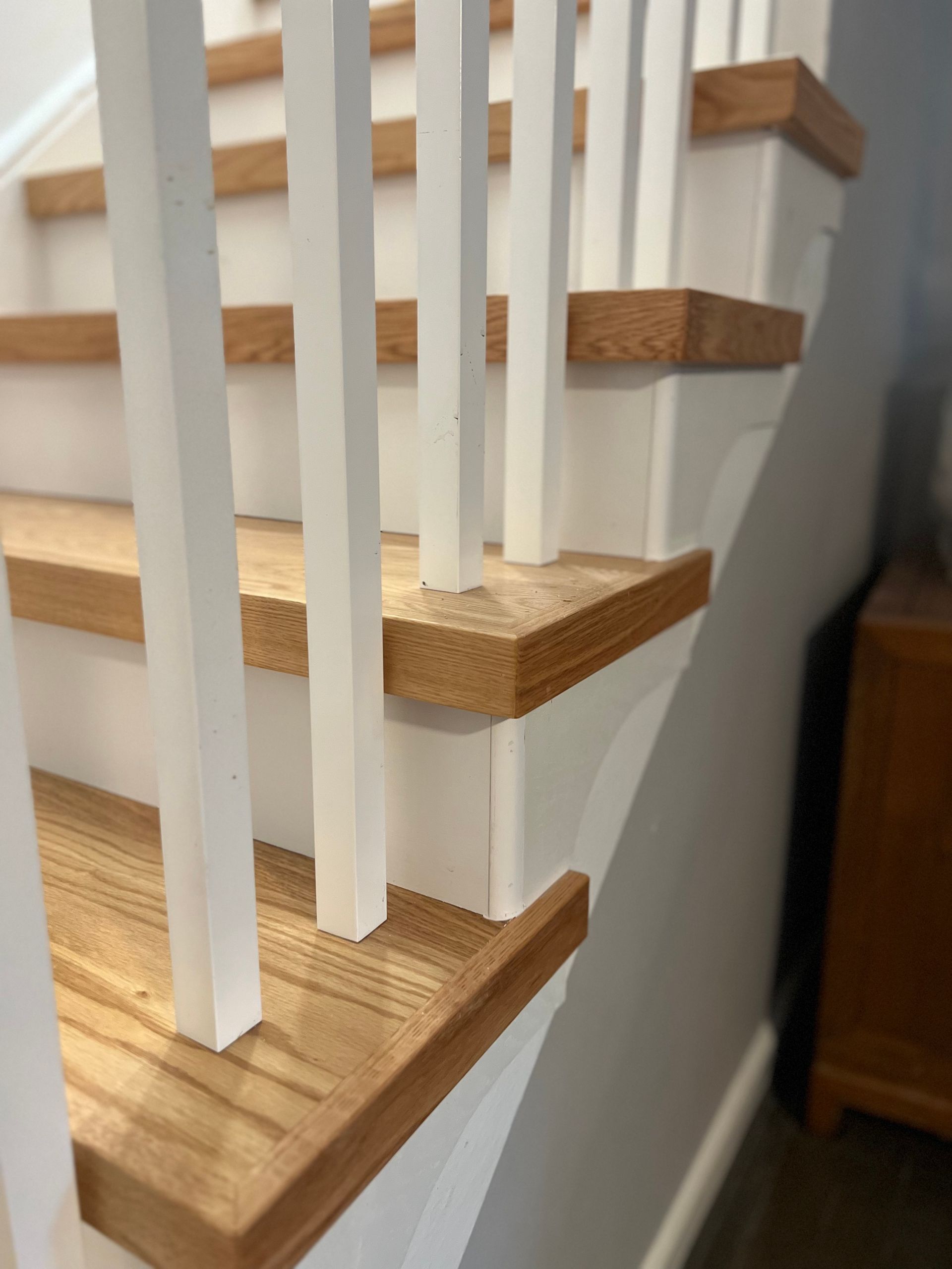 A close up of a wooden staircase with white railing