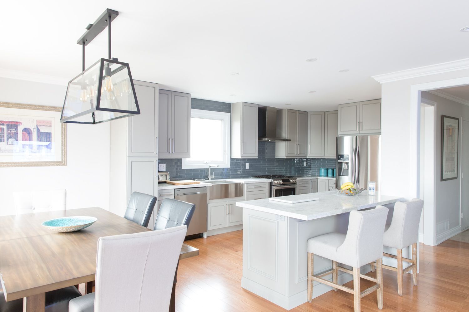 Open-concept kitchen and dining area with gray cabinets, a white island, and wooden floors.