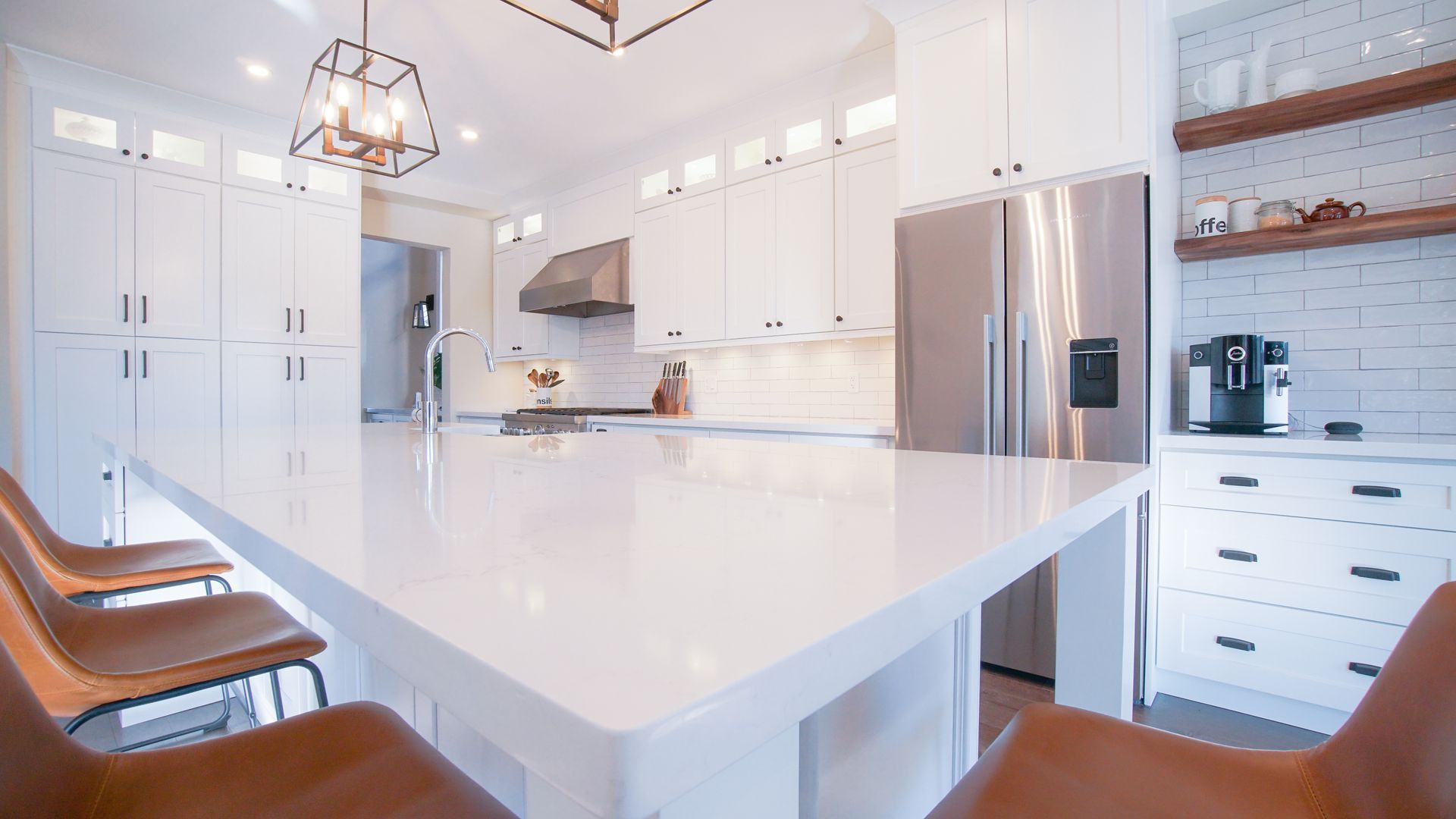 A kitchen with white cabinets , stainless steel appliances , a refrigerator , a table and chairs.