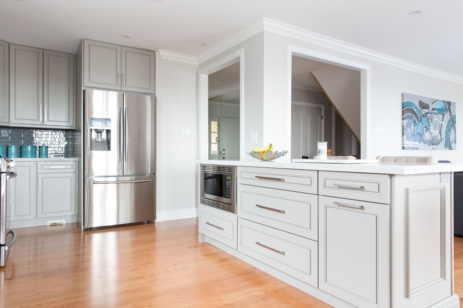 Spacious kitchen with light gray cabinets, stainless steel appliances, and hardwood floors.