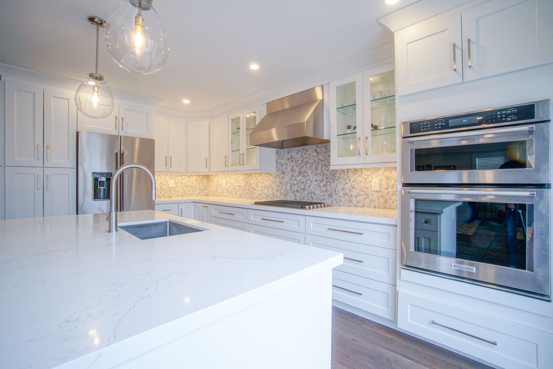 A kitchen with white cabinets, stainless steel appliances, and a large island.