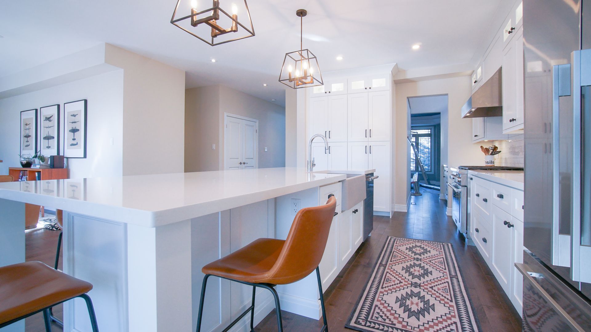 Modern kitchen with white cabinets, island, and brown leather bar stools.