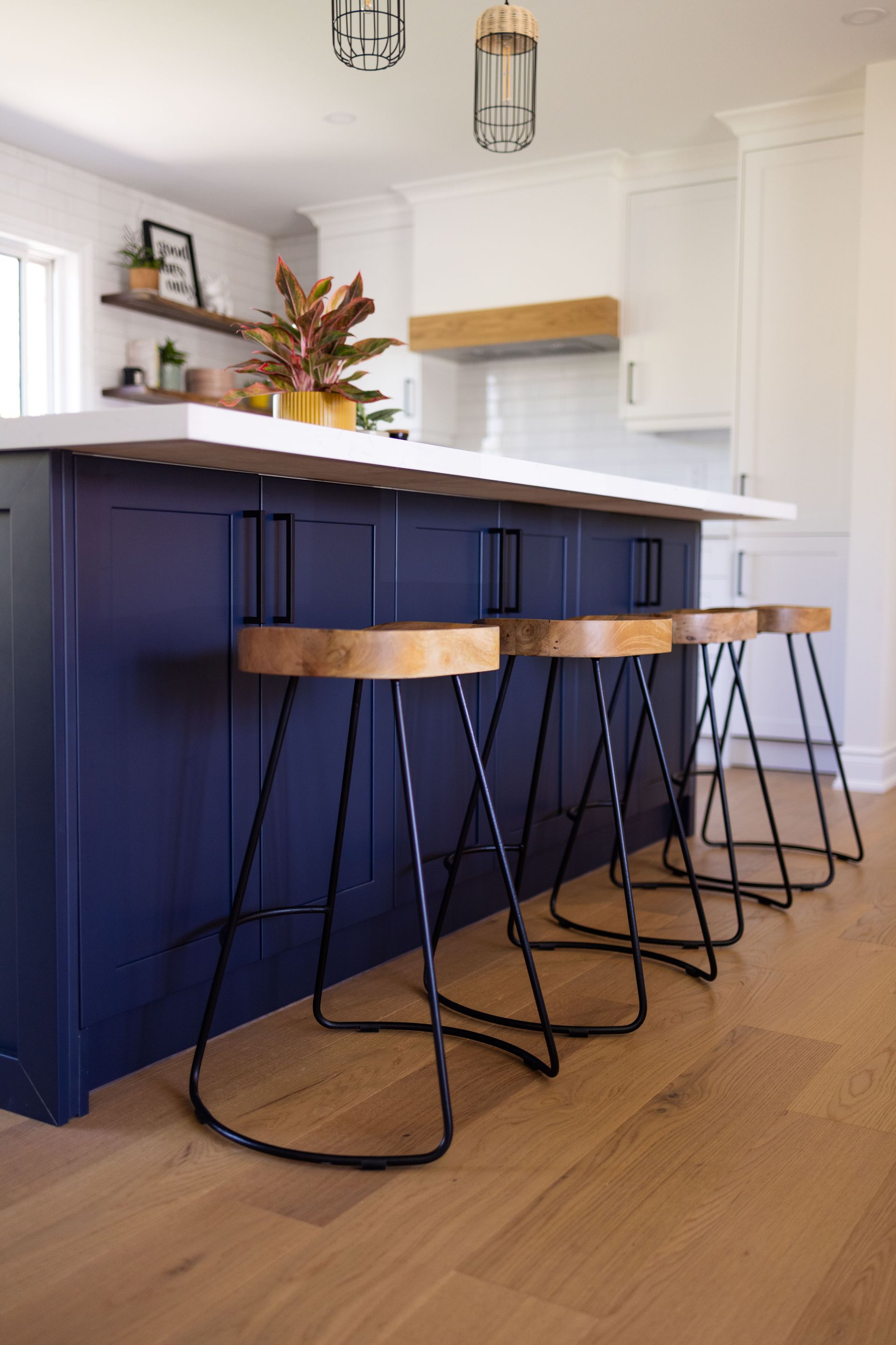 A kitchen with blue cabinets and wooden bar stools.