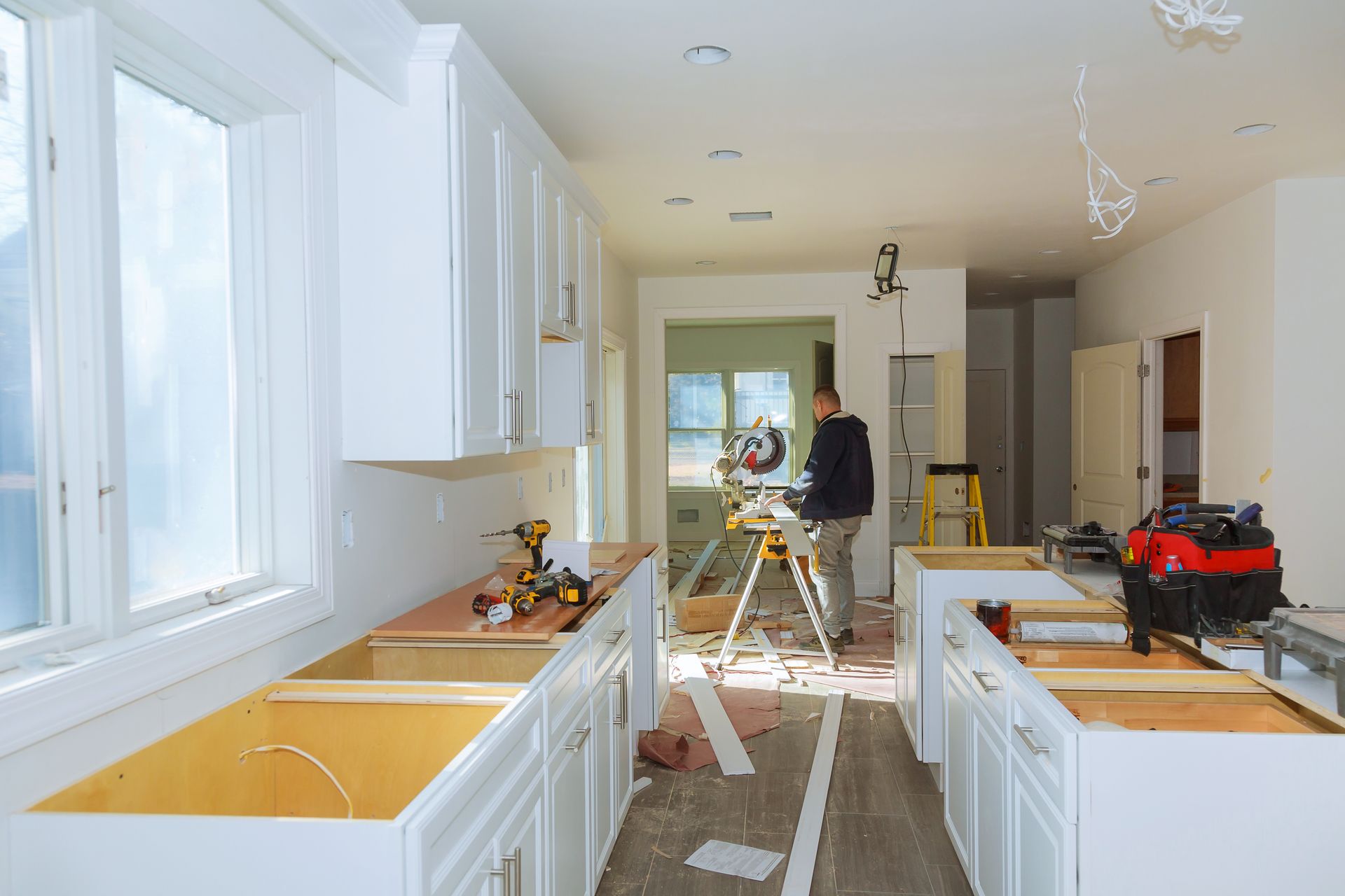 A man is standing on a ladder in a kitchen under construction.
