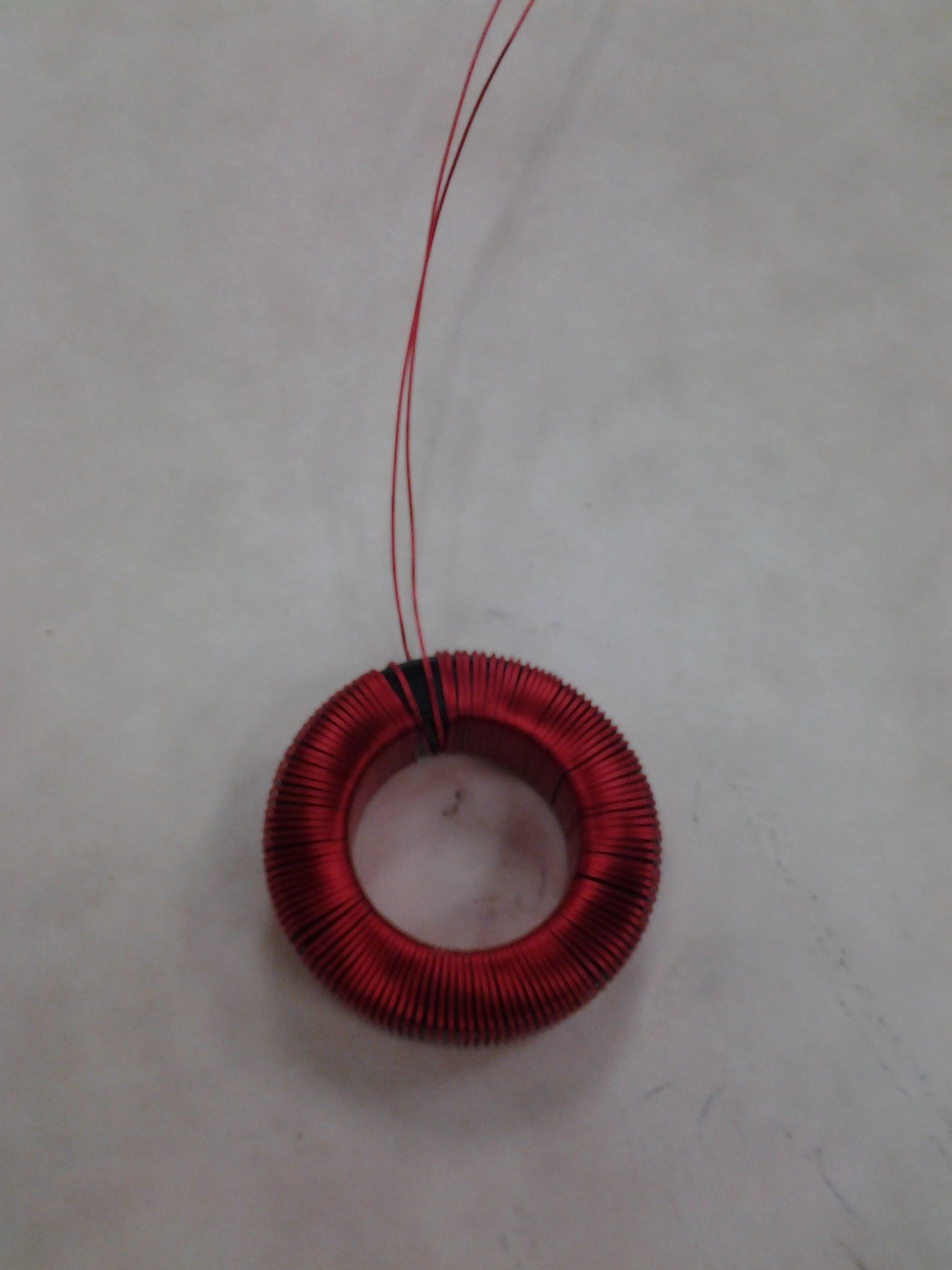 Red toroidal coil with two red wires, on a white background