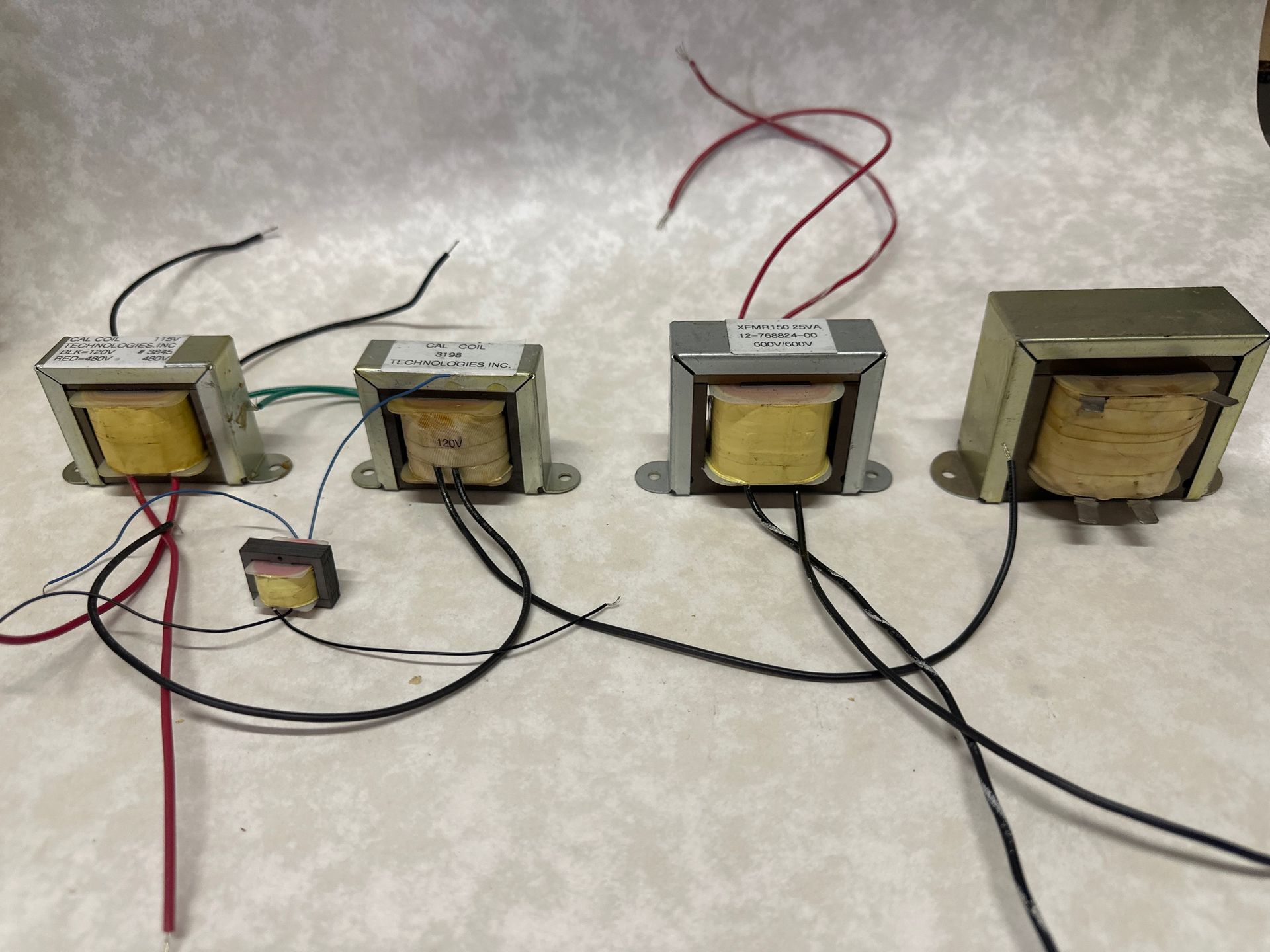 Four rectangular transformers of varying sizes with wires extending from them