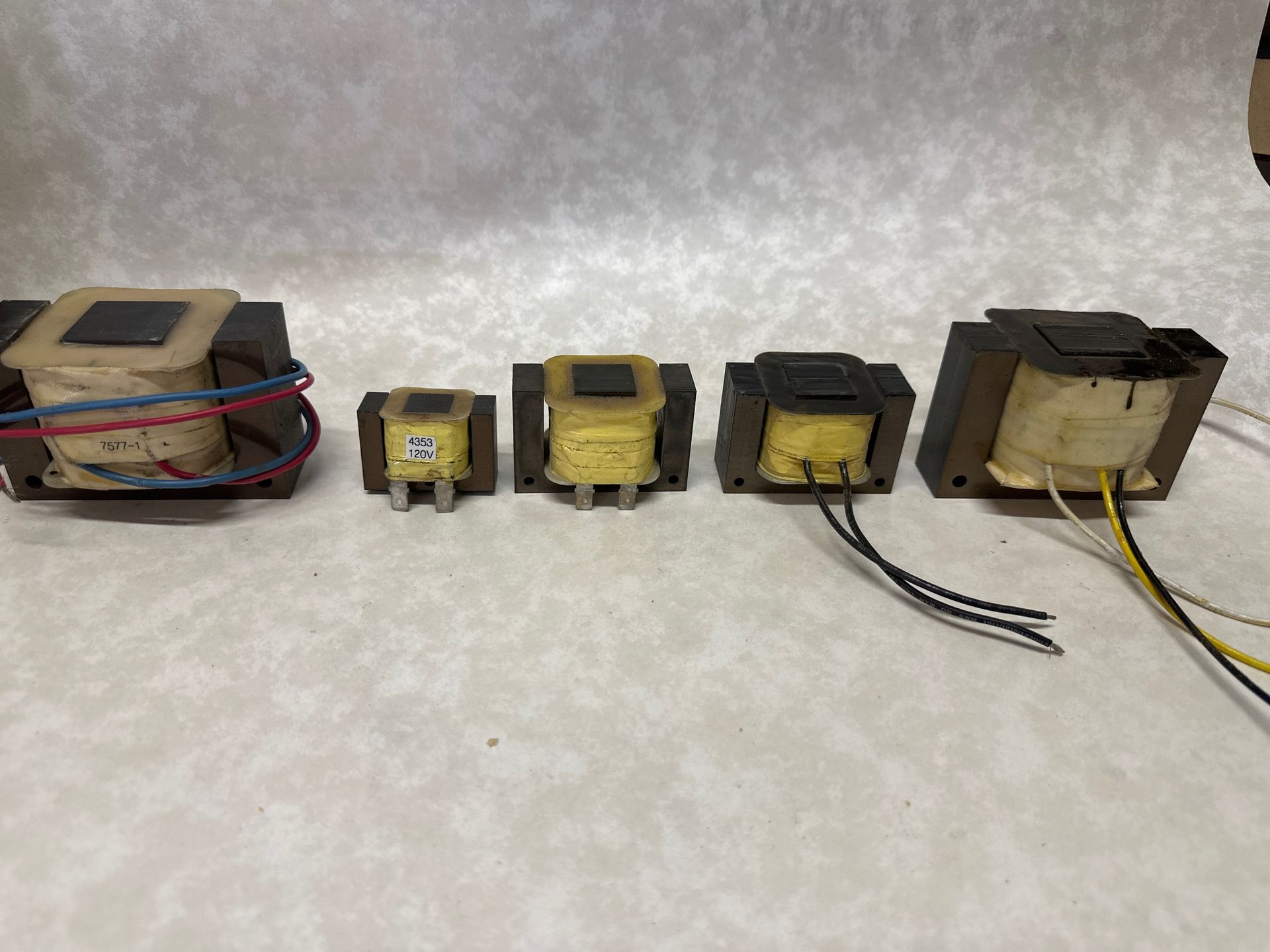 Five black transformers of varying sizes on a marbled surface