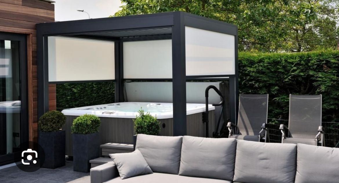 Vasca idromassaggio sotto un pergolato con pannelli per la privacy, accanto a posti a sedere all'aperto.