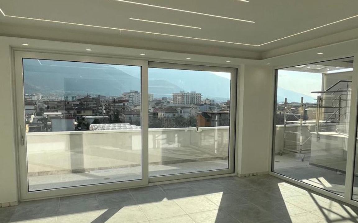 Camera luminosa con grandi porte scorrevoli in vetro con vista sulla città e sulle montagne.