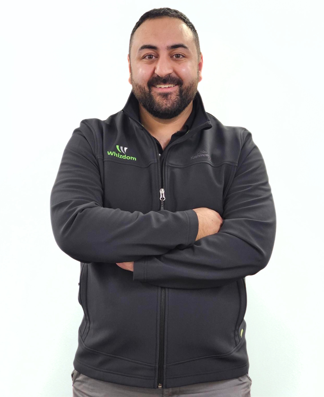 Man with curly hair and beard wearing a navy polo shirt, arms crossed, smiling at the camera.