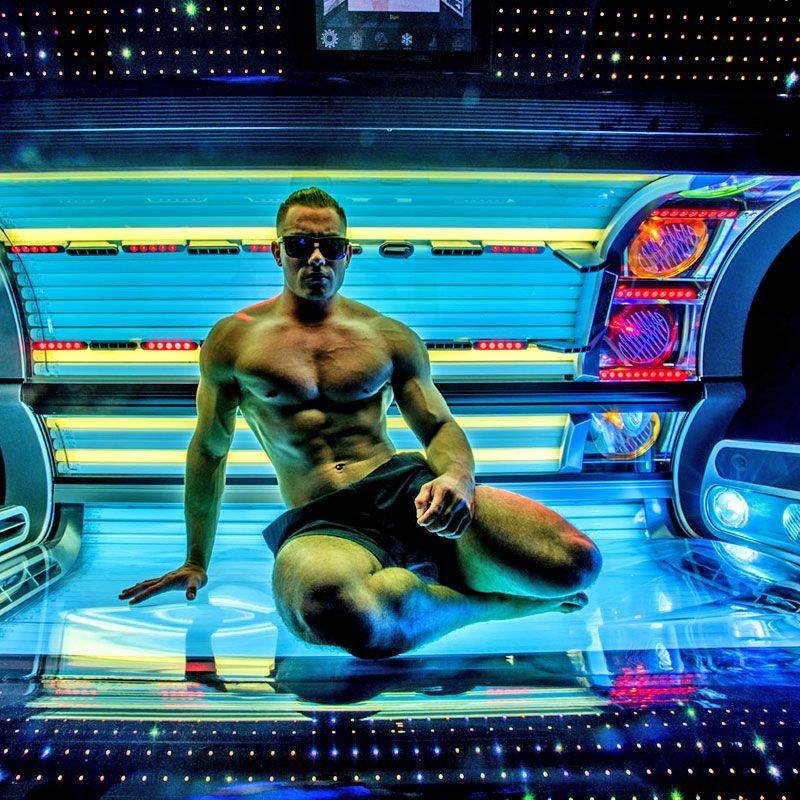 Ein Sportlicher Mann ohne Hemd sitzt auf einem Solarium