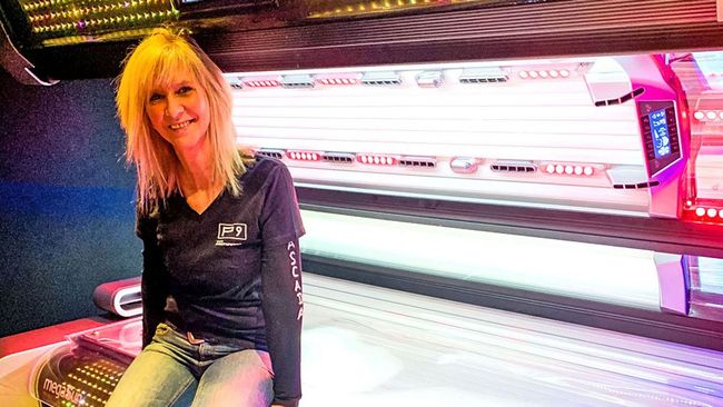 Kundenbetreuerin im SunWorld Solarium vor modernem P9-Solarium – persönliche Beratung inklusive.