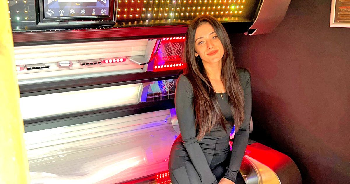 Kundenbetreuerin sitzt lächelnd auf modernem Solariumgerät bei SunWorld und bietet persönliche Beratung im Studio.