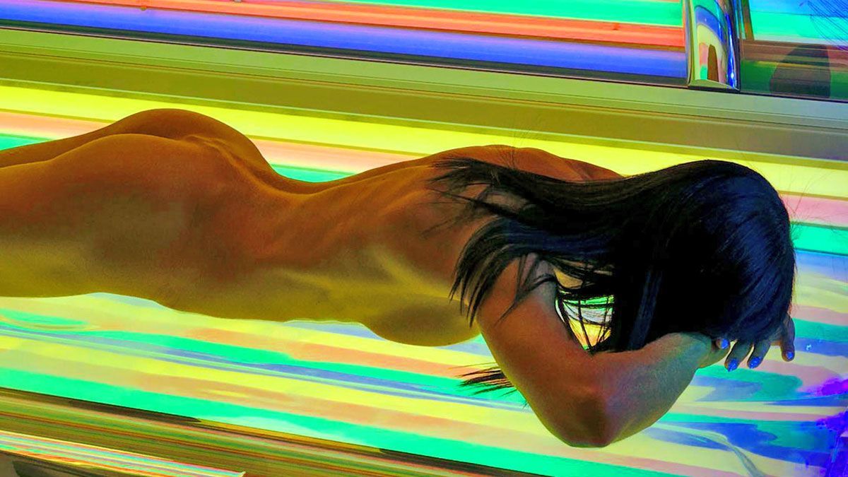 Attraktive Frau auf einer Sonnenbank die mit Rainbow Licht ausgestattet ist