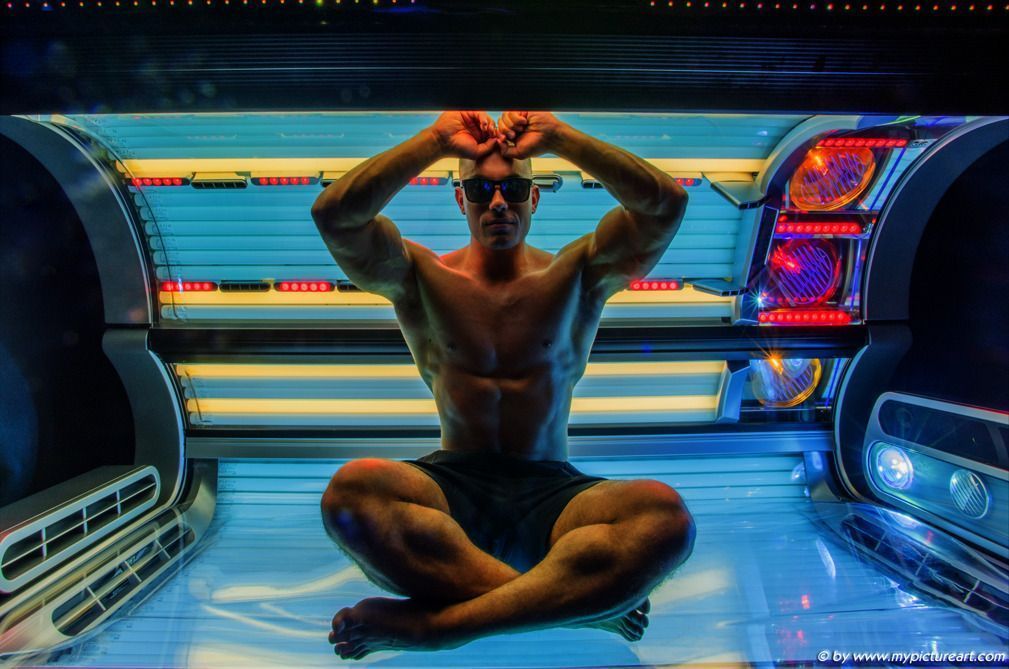 Muskulöser Mann sitzt meditativ im modernen Solarium – SunWorld Vitamin-D-Licht für Hautgesundheit, Wohlbefinden und neue Energie im Winter.