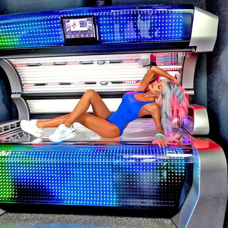 Eine Frau in einem blauen Badeanzug liegt auf einem Solarium